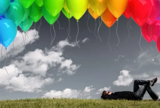 دراز کشیدن روی چمن با بادکنک های رنگی در آسمان